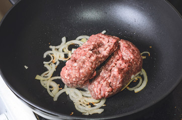 Onions and minced meat are fried in a frying pan. Close up