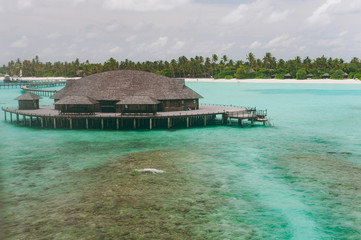 Luxury thatched roof honeymoon bungalow in a vacation resort in the blue lagoon of the Indian Ocean...
