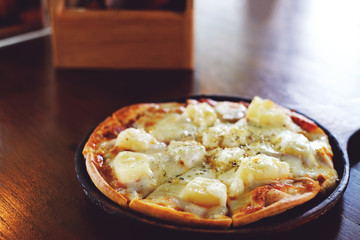 pizza with ham and pineapple on wood dinner table