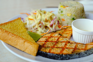 salmon grill steak serve with salad, bread and fried rice