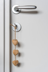 Heart shaped wooden key pendant with key in lock of white door