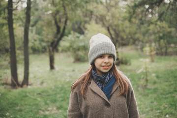 Outdoors lifestyle fashion portrait of pretty young woman walking on the autumn park. Holding maple leaves. Wearing stylish grey coat, Enjoying autumn nature. Autumn colors