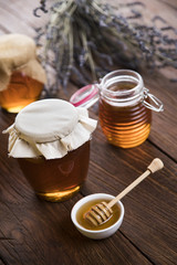 Honey in jar with honey dipper on wooden background 