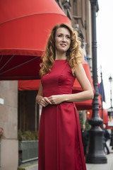 Beautiful elegant woman in a red dress on the street
