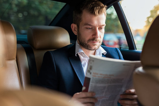 Handsome business man reading newspapers while traveling