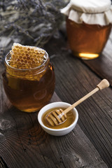 Honey in jar with honey dipper on wooden background 