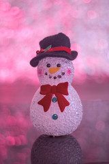 Christmas snowman decoration doll on top of a table casting a reflection