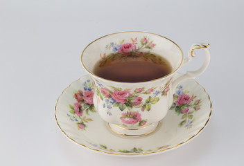Full antique teacup and saucer with rose and gold decoration isolated on white