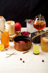 Set of various winter cocktails: mulled wine, eggnog, limoncello, old-fashioned, coconut margarita. Black background, white linen tablecloth. Vertical composition.