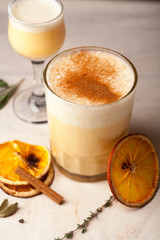 Two glasses with christmas eggnog drink decorated with cinnamon on dark background. Vertical composition.