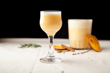 Two glasses with christmas eggnog drink decorated with cinnamon on dark background. Horizontal composition with copy space.