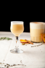 Two glasses with christmas eggnog drink decorated with cinnamon on dark background. Vertical composition.