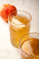 Two vintage glasses with apple cider on black background. Christmas beverages concept. Two red apples and rosemary sprig aside.  Warm backlight. Vertical composition.