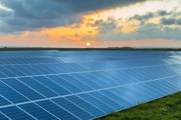 Solar panels at sunrise with cloudy sky in Normandy, France. Solar energy, modern electric power production technology, renewable energy concept. Environmentally friendly electricity production