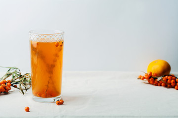 Warm sweet organic tea with sea buckthorn berries, thyme and honey. White background, natural lighting. Horizontal composition with copy space. Concept of beauty in simplicity.