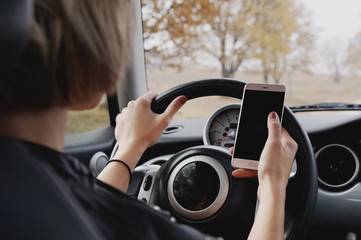 girl driving a car typing text on the phone and looking out the window