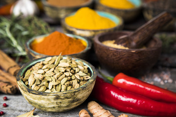 A selection of various colorful spices on a wooden table in bowls