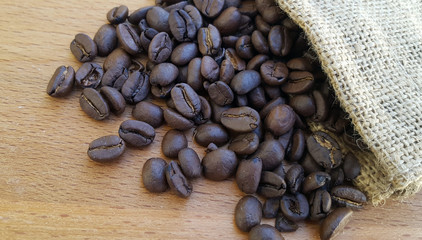 Coffee beans in a bag on wooden background