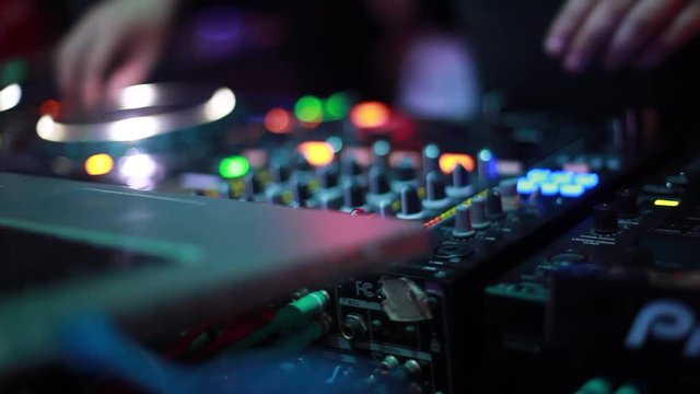 Close up of hands of DJ plays music mixing and scratching on turntable music equipment. Professional music equipment with lights and controls being played by male disc jockey. 1920x1080