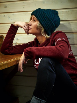 Young hipster woman in hat and sweater sitting in cafe