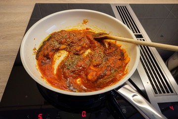 Bratpfanne auf Herd mit Kochlöffel und Tomatensauce