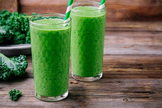 Healthy detox green smoothie with kale in a glass on wooden background