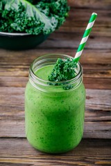Healthy detox green smoothie with kale in mason jar on wooden background