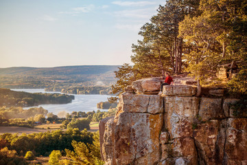 Man sitting on rock outcrop at Gibraltar Rock, Wisconsin. - obrazy, fototapety, plakaty