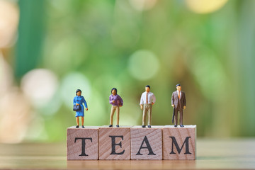 Miniature 4 people standing on wood word team as background business concept with copy space.