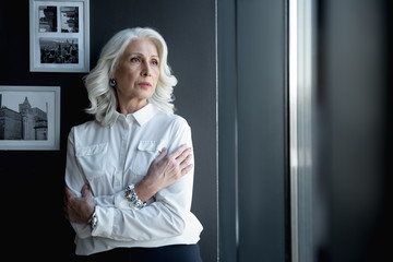 Pensive old lady is standing in office