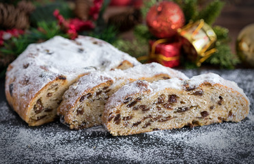 Weihnachtlicher Christstollen in Scheiben auf dunkelem Untergrund
