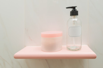 Soap and shampoo dispensers on shelf of bathroom interior