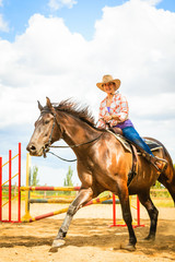 Cowgirl in western hat doing horse jumping