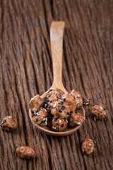 Fried peanuts sesame snack in spoon on the wood table