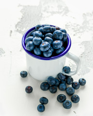 Freshly picked Blueberries in vintage mug with green leaves on top