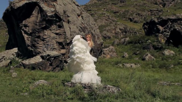 beautiful girl in a wedding dress among stones and mountains
