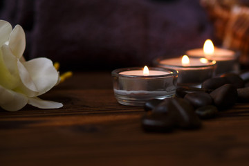 Obraz na płótnie Canvas A candle in a glass vase, decoration and various interesting elements on a dark wooden background. Candles burning. Set for spa and massage. stones for massage
