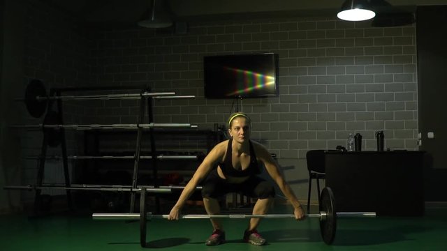 A strong girl makes a snatch of a bar in the gym. Slow motion