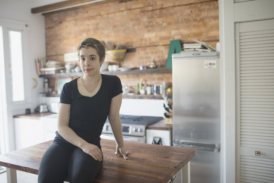 Transgender person sitting on their kitchen counter