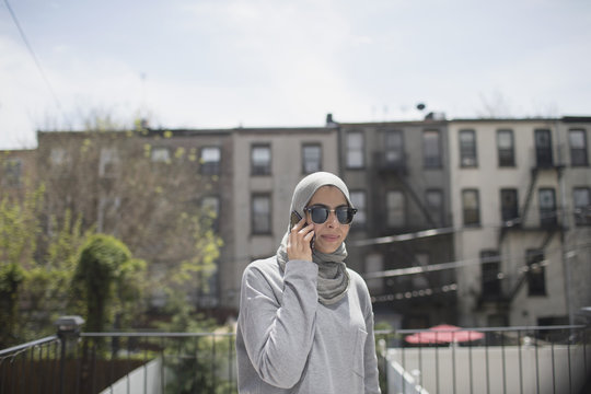 Muslim woman wearing a hijab and sunglasses taking a phone call