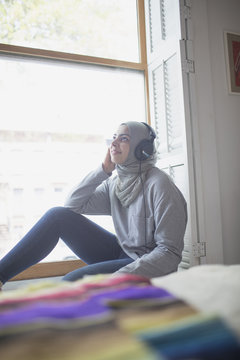 Muslim woman wearing a hijab listening to music