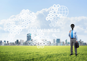 Camera headed man standing on green grass against modern cityscape