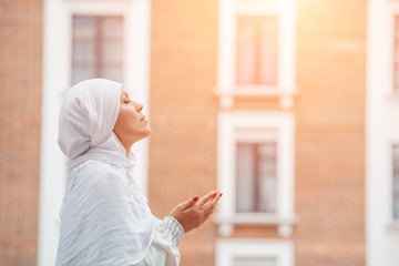 A young muslim woman praying in white hijab