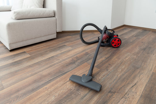 Vacuum cleaner on the wooden floor. Cleaning home