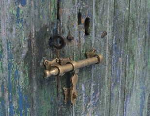 Antique door with distressed paint finish in blues and greens with brass door furniture