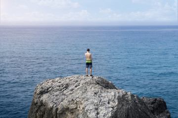 Fototapeta na wymiar young man standing on a cliff