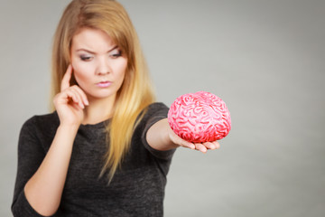 Woman thinking and holding fake brain