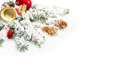 Christmas decoration. Branch christmas tree, christmas bells, red balls and cones spruce on snow on white background with space for text.