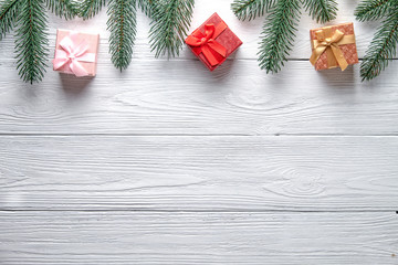 Christmas background. Branches of a Christmas tree and gift boxes on a wooden background with copy space.