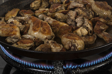 Paella valenciana de pollo y arroz, friéndose.